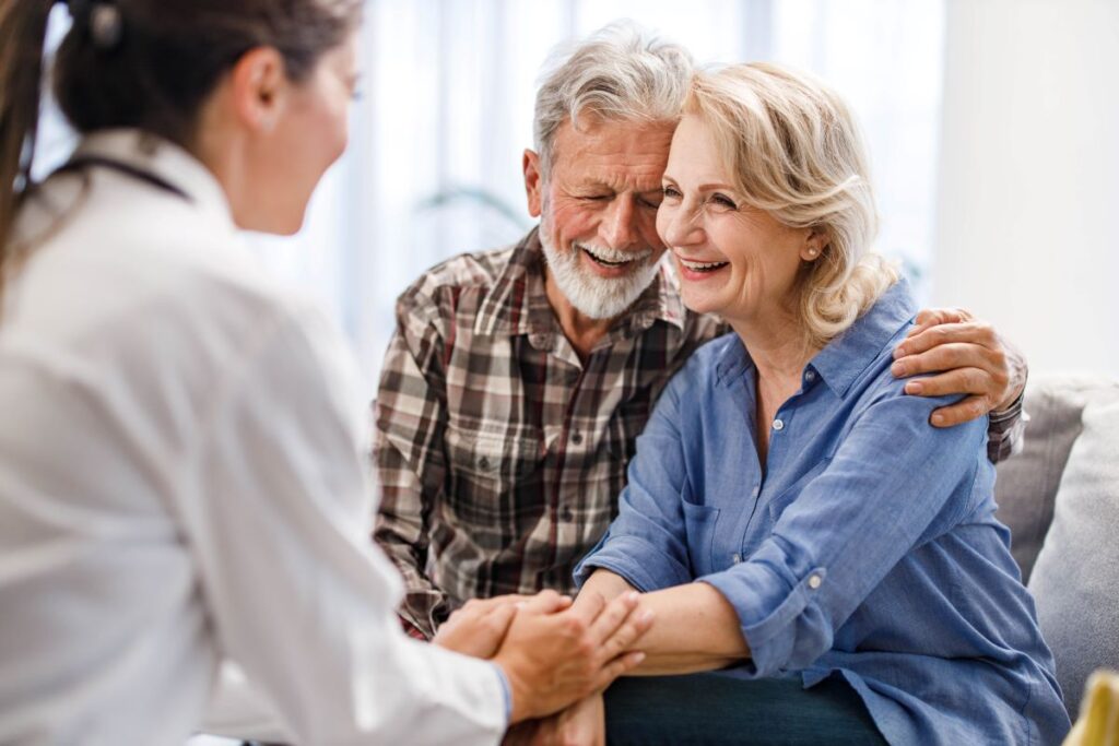Happy senior couple communicating with their caregiver at doctor's office.