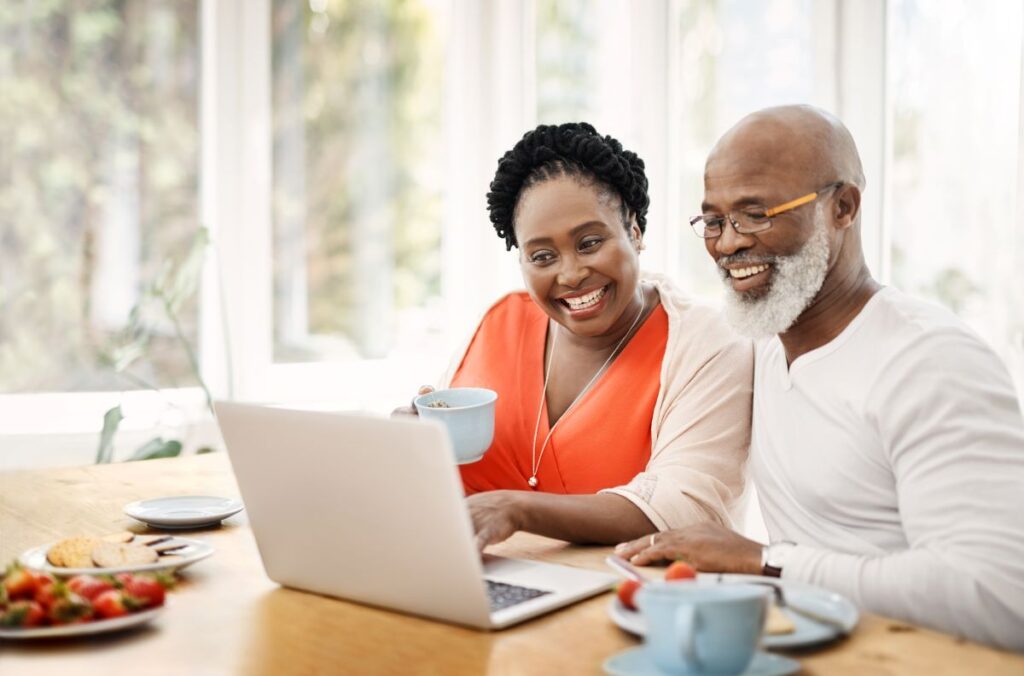 Shot of a happy mature couple using a laptop while having breakfast together at home